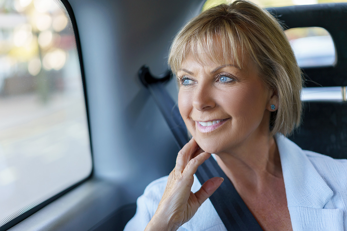 Portrait of a beautiful senior woman riding on a taxi and smiling - transport concepts